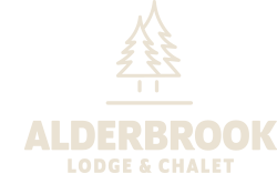 A logo featuring two stylized evergreen trees above a horizontal line. Below the line, text reads "ALDERBROOK LODGE & CHALET" in capital letters. The design is presented in a beige color.